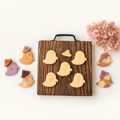 Finished Halloween ghost cookies with playful expressions and small witch-hat cookies