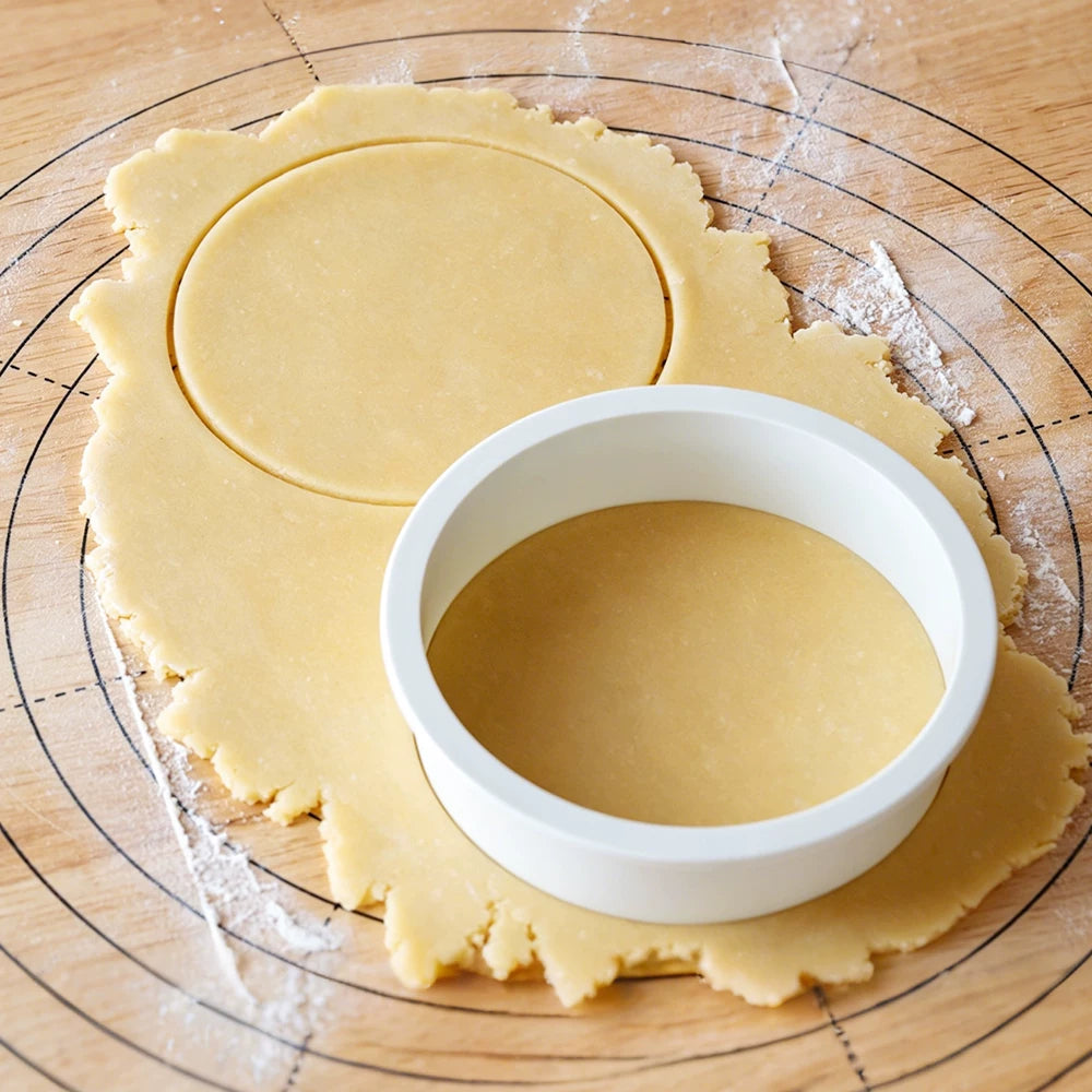 White round pastry cutter cutting a circle from rolled dough