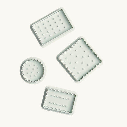 Original photograph of four pale mint biscuit stamps and cutters with the background cleaned to ivory