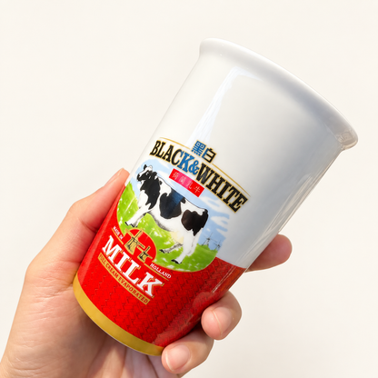 Black & White ceramic milk tea cup held in hand against an ivory background