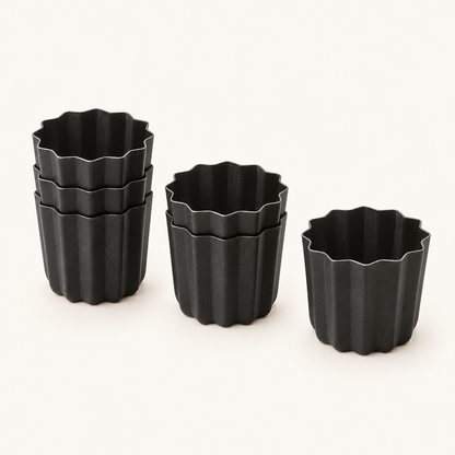 Set of six black fluted canelé molds arranged in groups of three, two and one